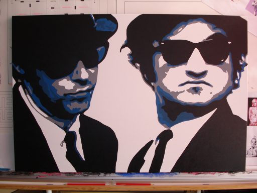 Two men in black suits and sunglasses, with a bold blue and white abstract background.