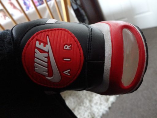 Black and red Nike Air sneaker close-up, featuring the logo and visible sole.