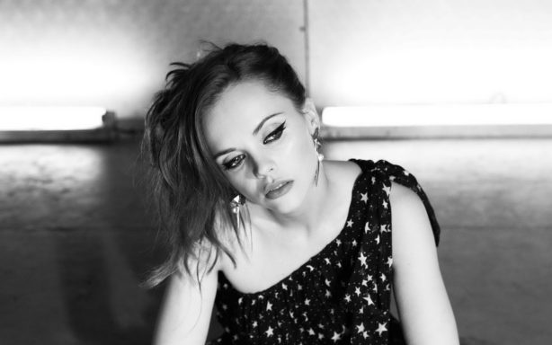 Woman with a thoughtful expression, wearing a sparkly top in black and white.